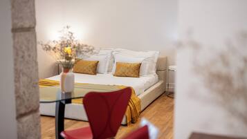 A bedroom with a bed, two pillows, a bedside table, a lamp, and a chair.