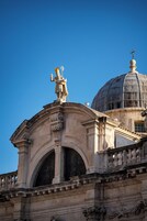 Um edifício histórico com uma cúpula imponente e estátuas.