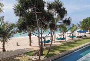 A poolside area with a view of the beach, lounge chairs, and umbrellas. - Lantern Boutique Hotel by Reveal (Kamburugamuwa)