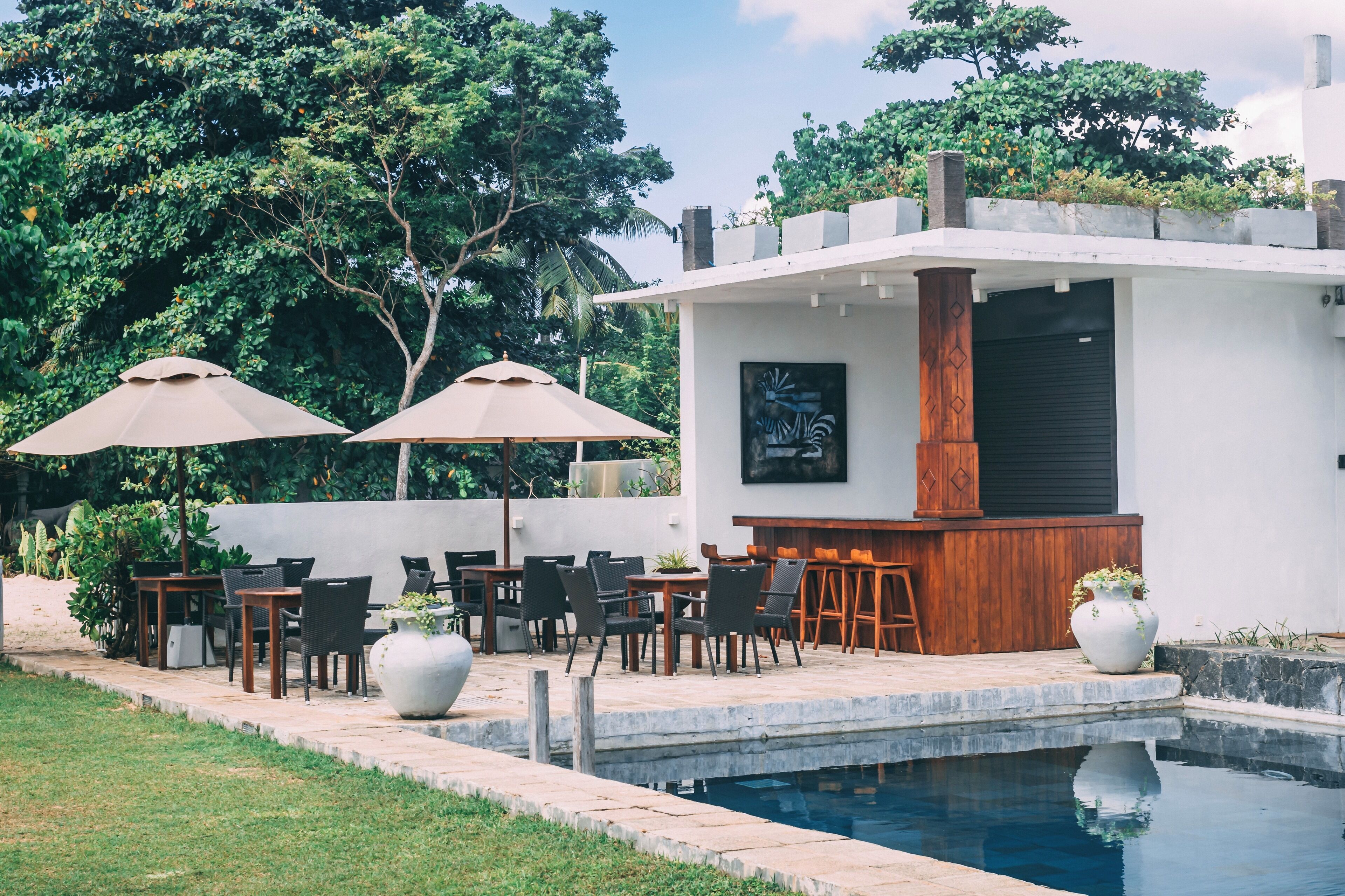 Un área de piscina al aire libre con un bar y asientos, rodeada de follaje y árboles.