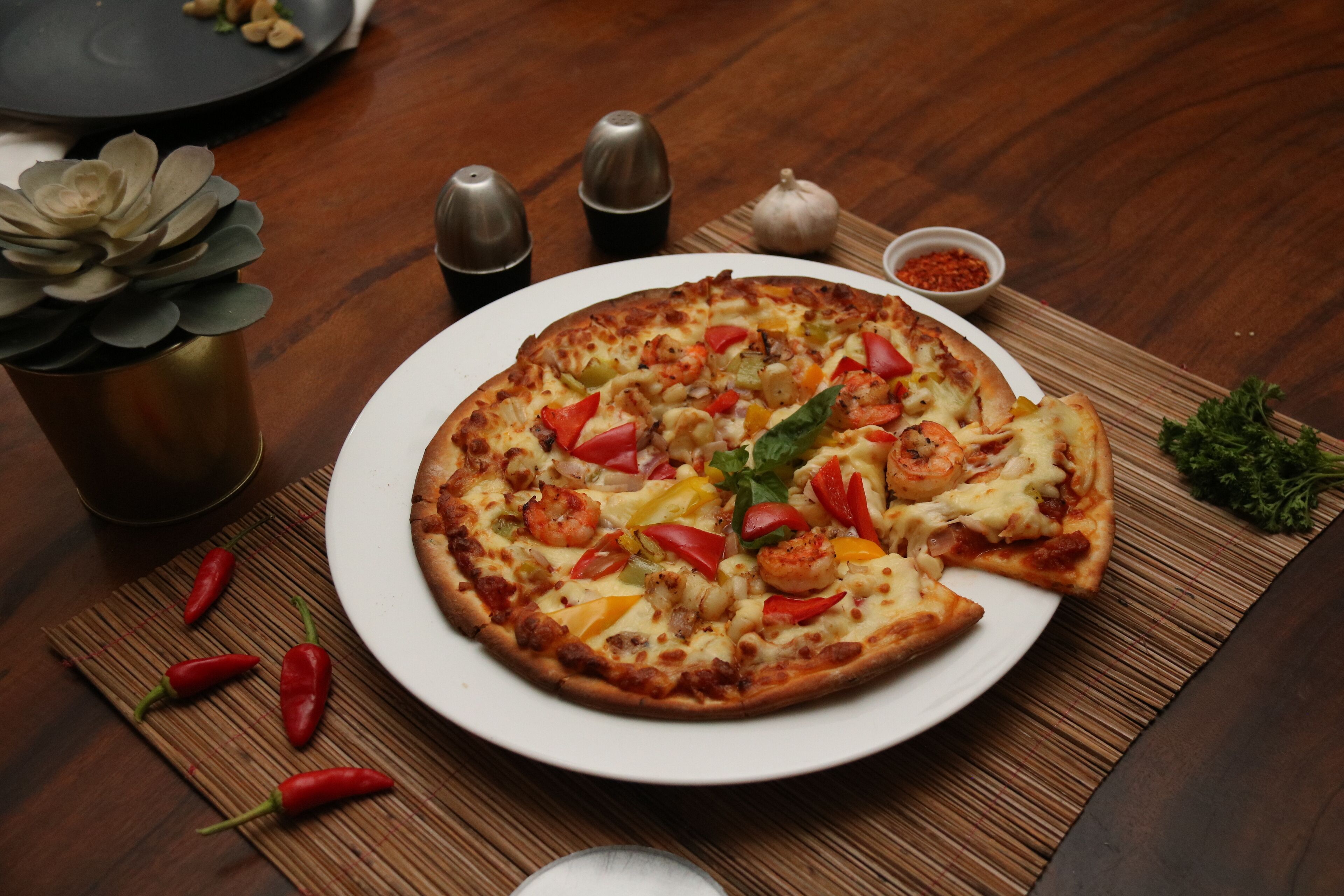 Pizza sobre un plato blanco, con una mesa de madera de fondo.