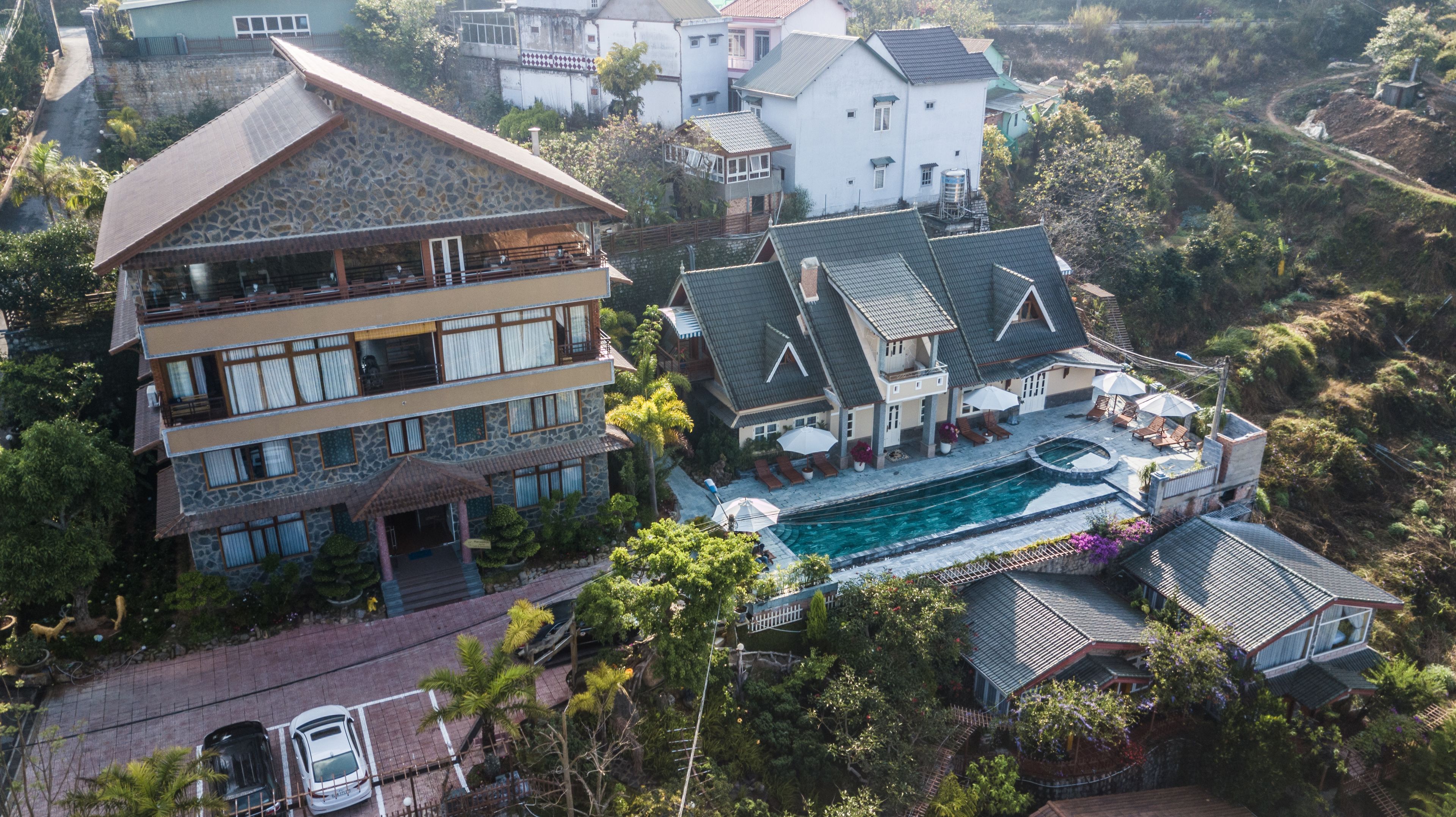 A multi-story house with a swimming pool, surrounded by lush greenery.