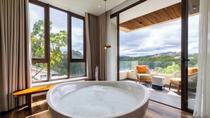 A modern bathroom with a large bathtub, large windows, and a balcony with outdoor furniture. - Zen Valley Dalat (Xuan Huong - Da Lat)