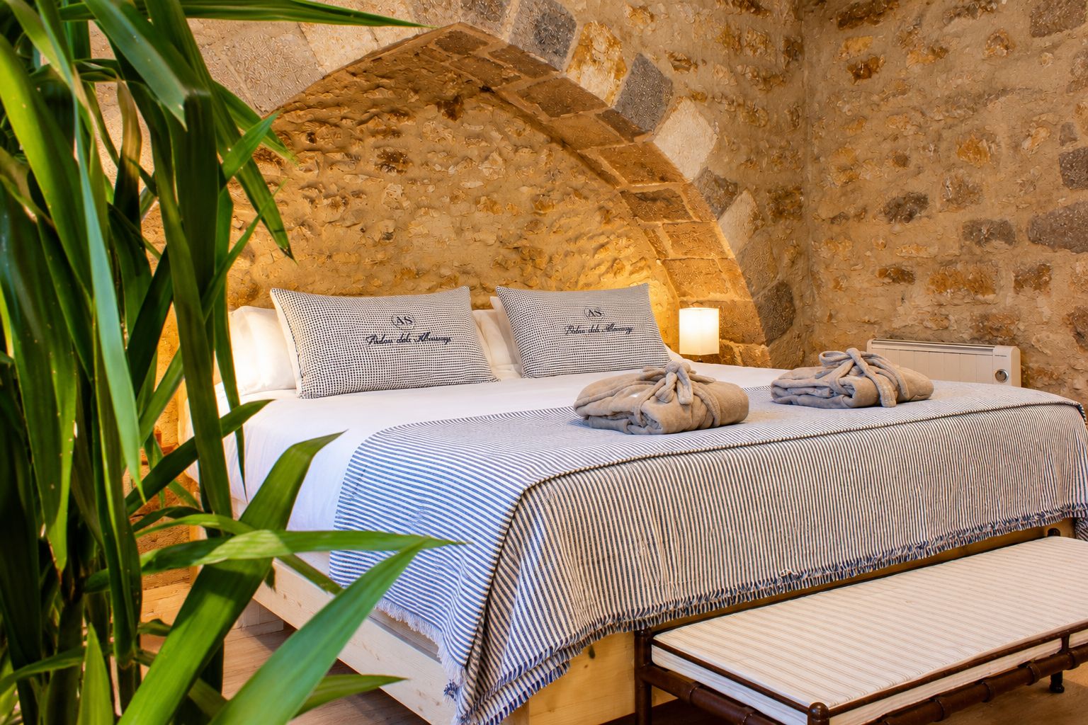 Un lit avec une couvre-lit à rayures, deux oreillers et une lampe de chevet.