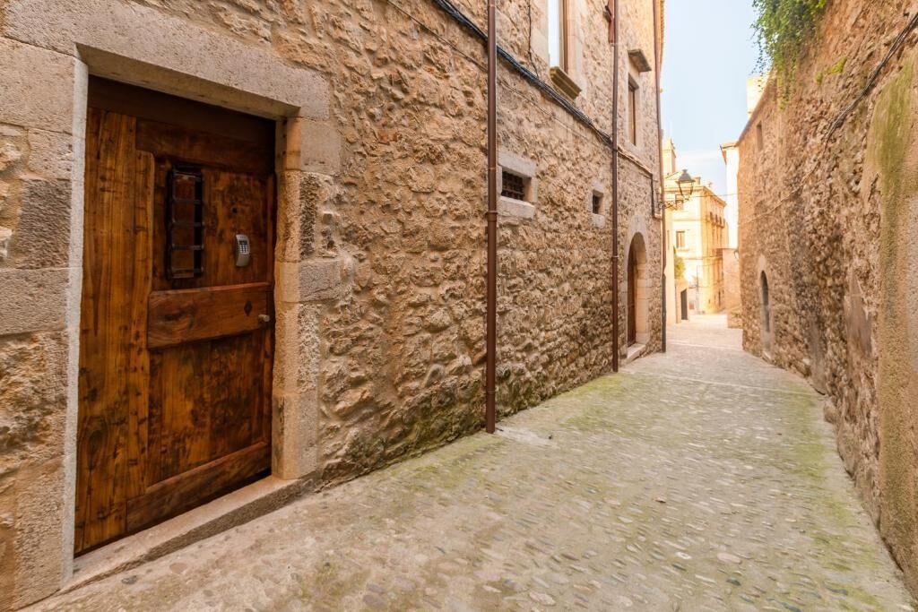 A narrow cobblestone street flanked by stone buildings with wooden doors and small windows.