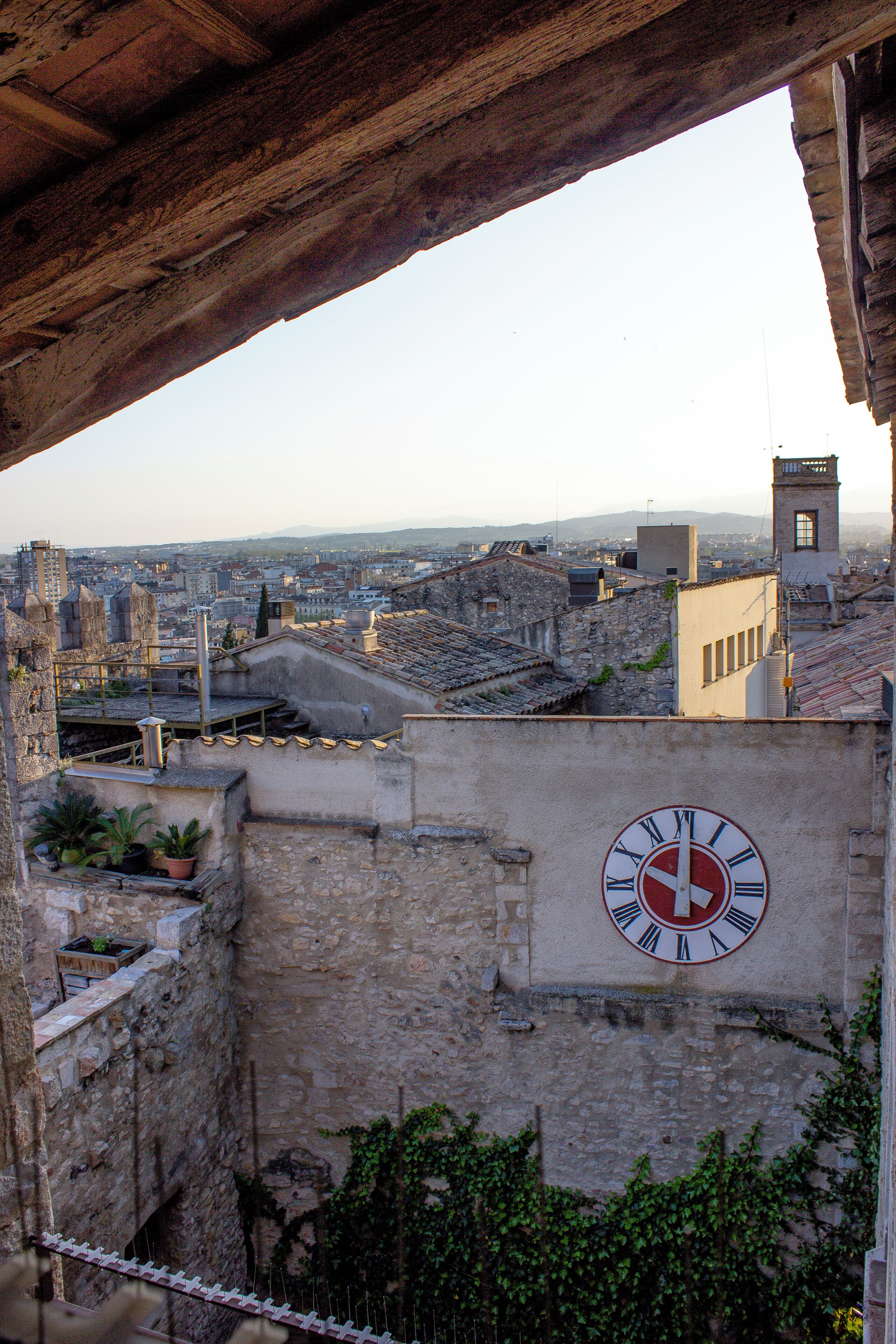 A clock on a building with a view of a cityscape.