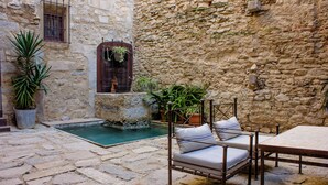 Un patio de piedra con piscina, cama y plantas en macetas.