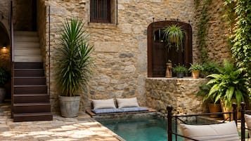 Un bâtiment en pierre doté d’une piscine, d’un espace extérieur aménagé et d’un escalier.