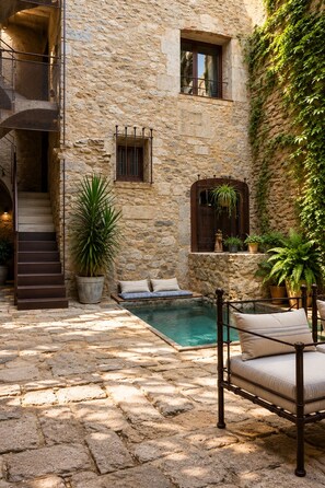 A stone building with a pool, outdoor seating, and a staircase. - AS Palau dels Alemanys (Girona)