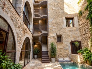 A stone building with a central staircase, a small pool, and potted plants. - AS Palau dels Alemanys (Girona)