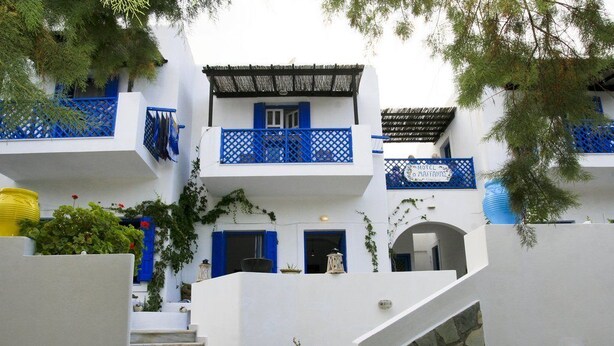 A white building with blue accents, a staircase, and a sign indicating a hotel. - Maganas Hotel (Astypalaia)