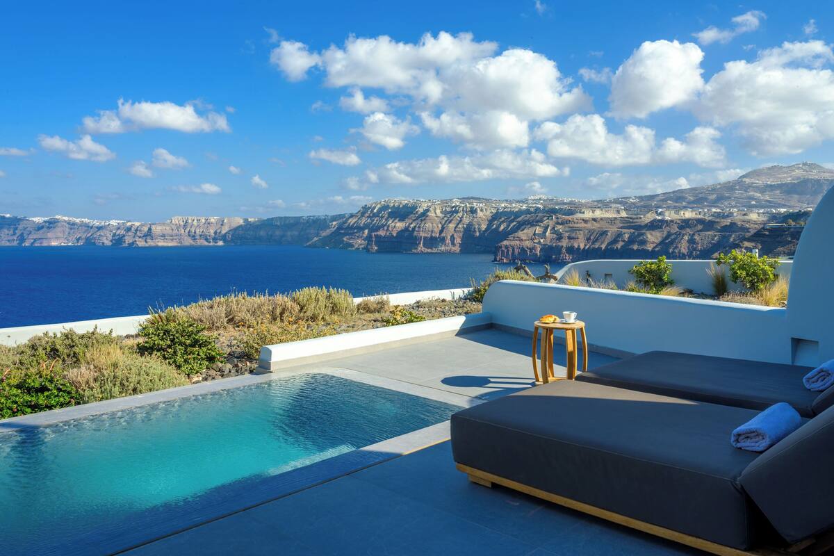 A poolside area with a view of the sea and cliffs.
