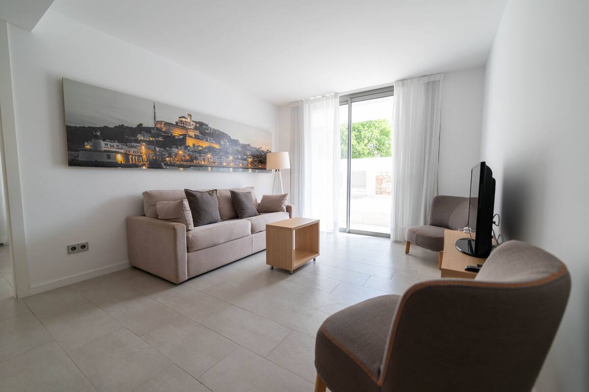 A modern living room with a sofa, armchair, and a flat-screen TV.