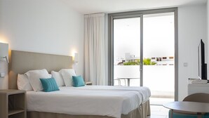 Ett hotellrum med en stor säng, ett skrivbord, en stol och en balkong med utsikt.