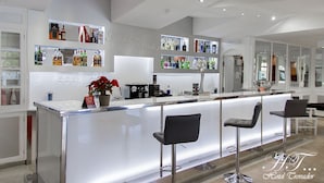 A modern hotel bar with a sleek bar counter, multiple seating options, and a variety of liquor bottles displayed on shelves.