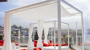 A white canopy bed with red pillows and a view of the city.