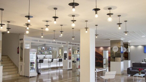 A modern hotel lobby with a reception desk, bar area, and seating.