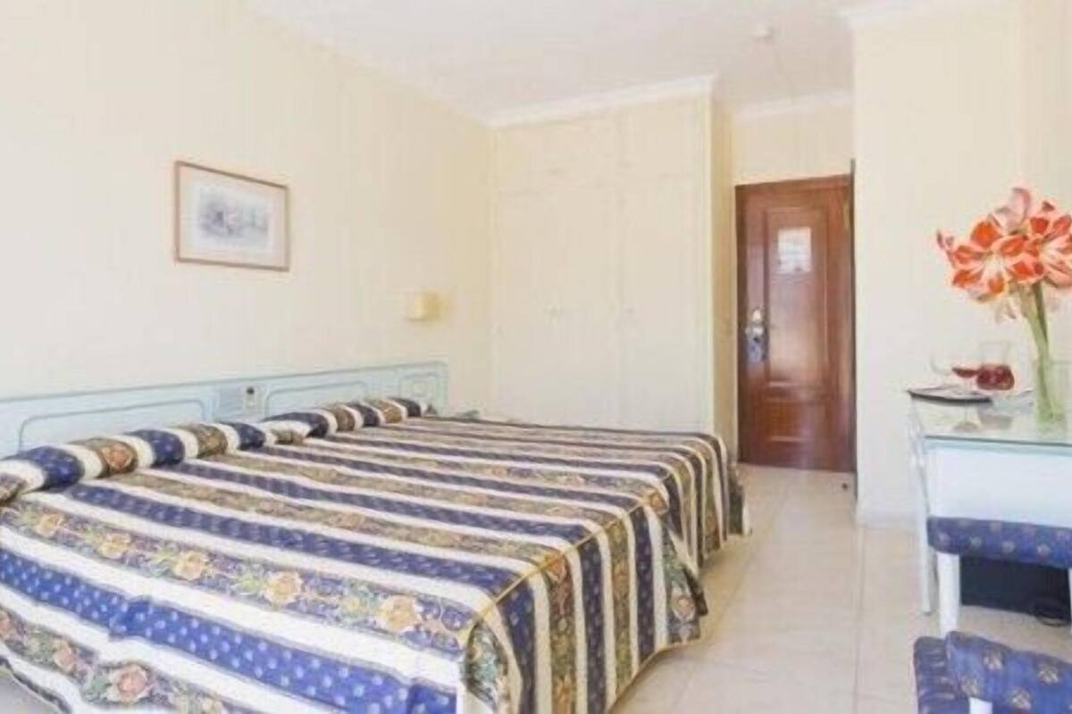 A room with two beds, a desk, and a mirror.