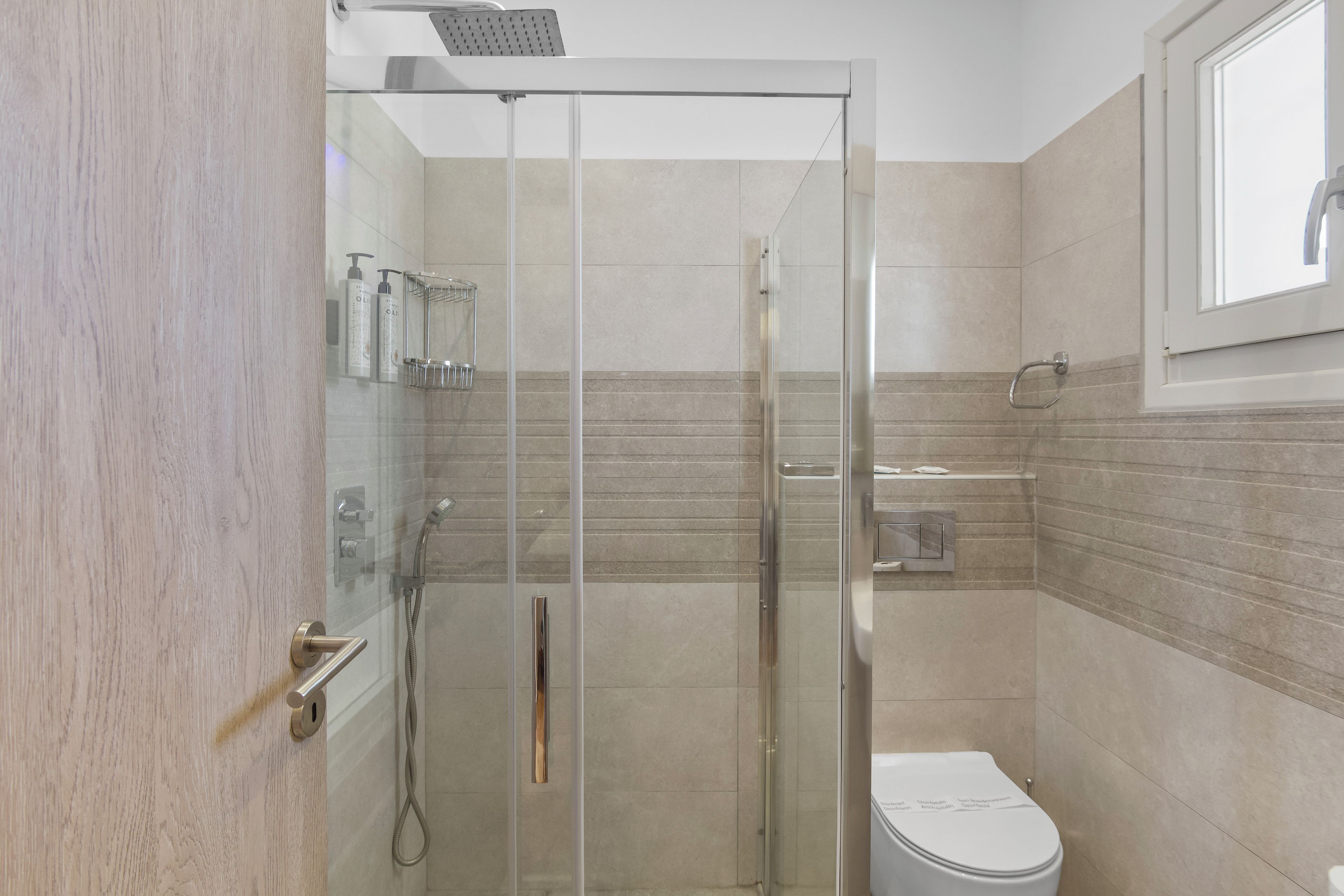 A modern bathroom with a glass shower enclosure, a toilet, and a sink.