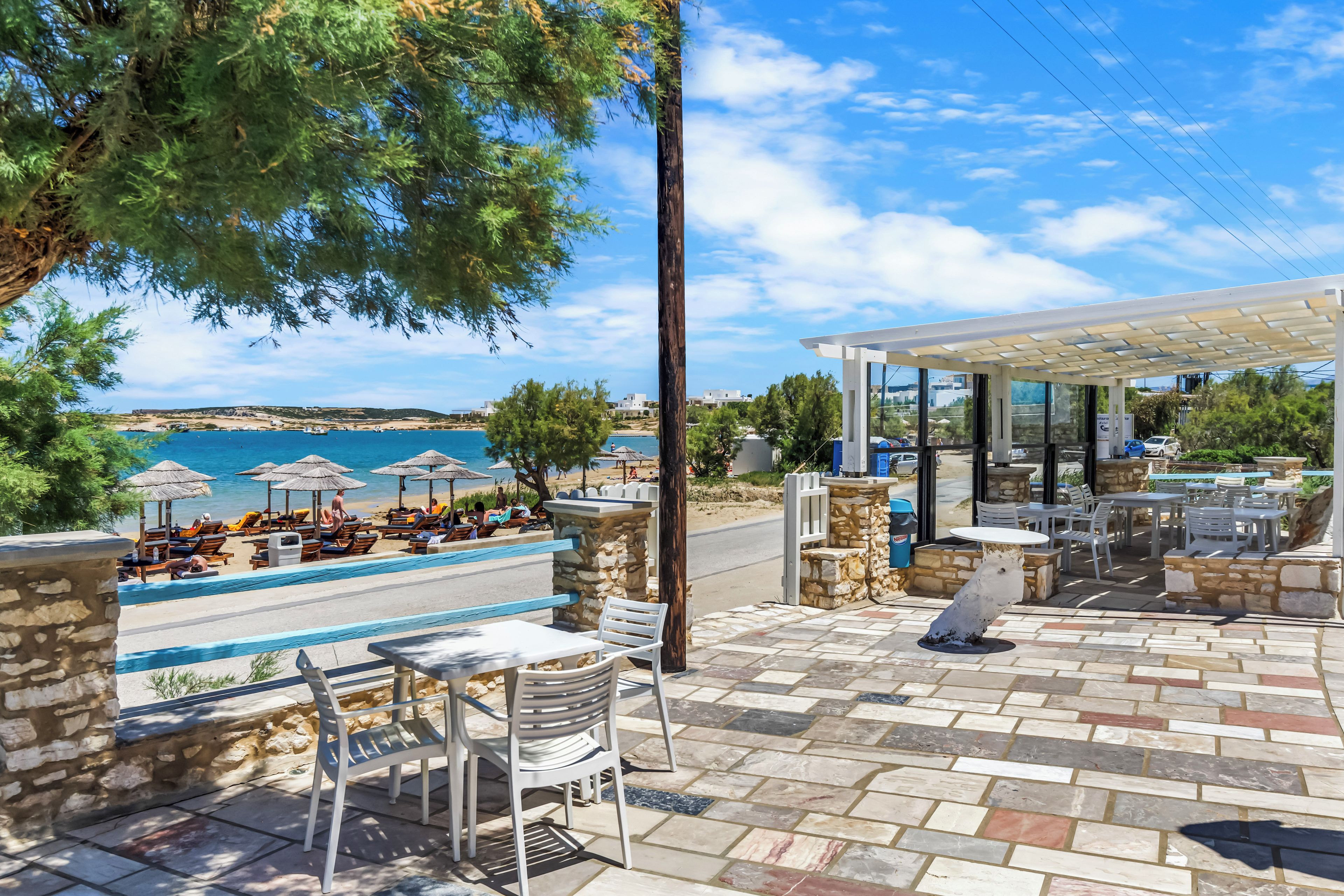 An outdoor seating area with stone walls, a view of the sea, and umbrellas.