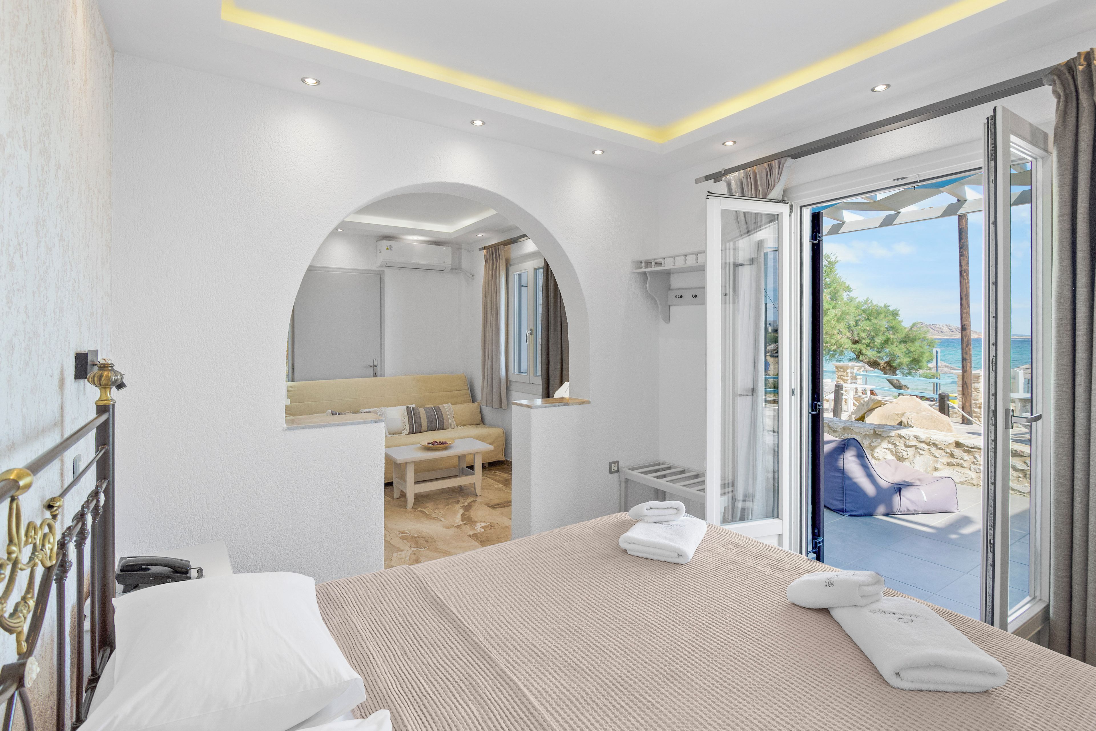 A hotel room with a bed, a bathroom, and a balcony with a view.