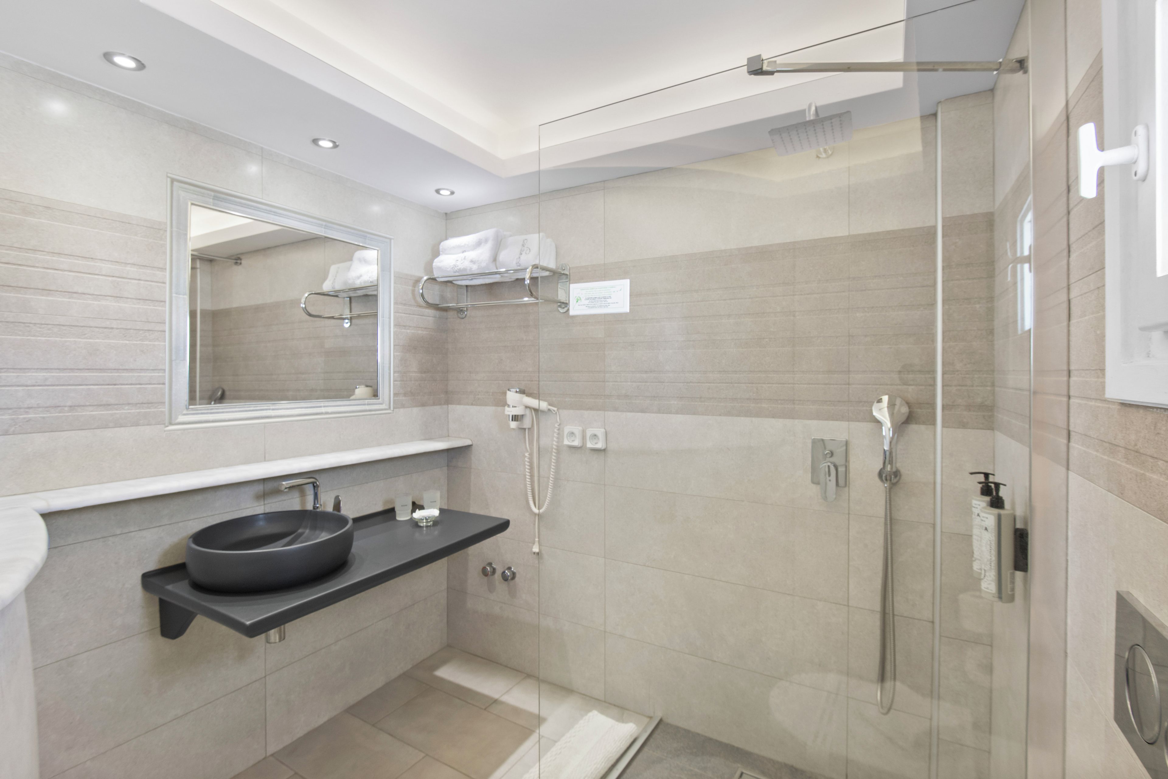 Un baño moderno con cabina de ducha de vidrio, un lavabo redondo y un espejo sobre el encimera.