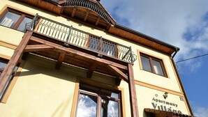 A building with a balcony, a sign reading "Apartmany Village," and a clear blue sky in the background. - Apartmány Village (Velky Slavkov)