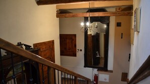 A staircase with wooden railings and a chandelier above. - Apartmány Village (Velky Slavkov)