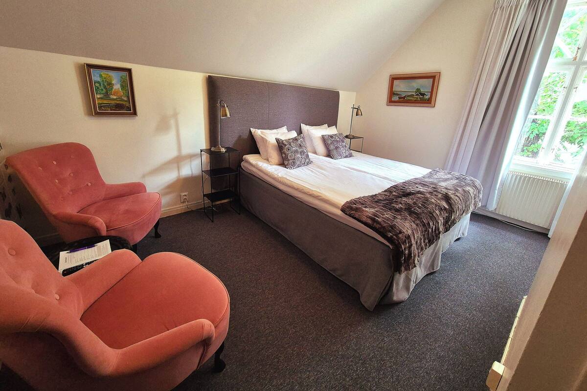 A hotel room with a bed, a nightstand, a desk, and a chair.