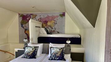 A dorm-style room with a bunk bed, a world map on the wall, and two bedside tables with lamps.