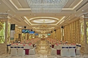 A banquet hall with rows of tables, a chandelier, and a television screen. - Hongchanglong Hotel (Nanning)