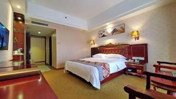 Een hotelkamer met een groot bed, een houten hoofdbord, twee nachtkastjes, een spiegel en een houten stoel.