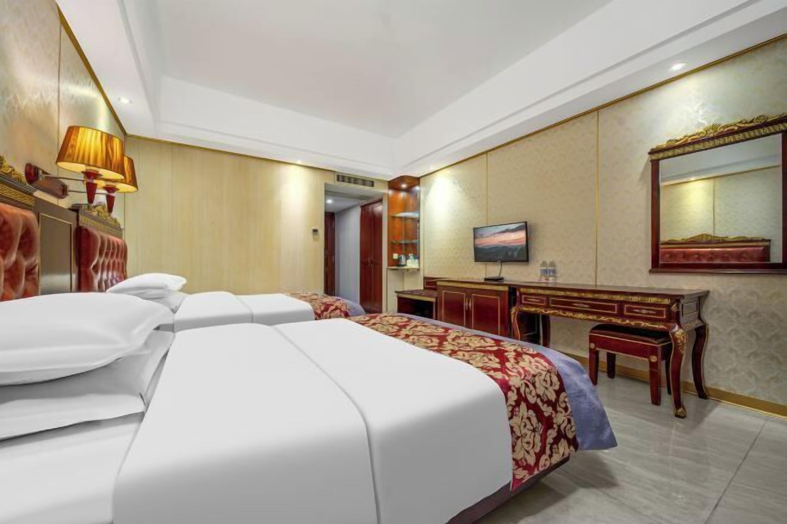 Een hotelkamer met twee bedden, een bureau, een televisie en een spiegel.
