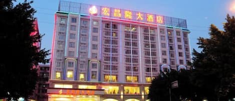 A multi-story hotel with illuminated signage and a row of windows on the ground floor.