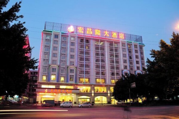 A multi-story hotel with illuminated signage and a row of windows on the ground floor.