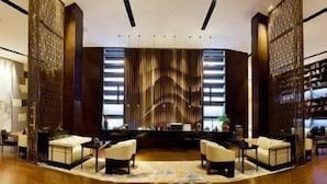 A modern lobby with a curved wooden floor, a central seating area with sofas, and a decorative wall with vertical lines. - Ramada Plaza by Wyndham Changsha South (Changsha)