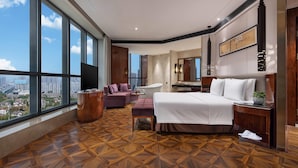 A modern hotel room with a large bed, a sofa, a vanity, and a view of the city. - Ramada Plaza by Wyndham Changsha South (Changsha)
