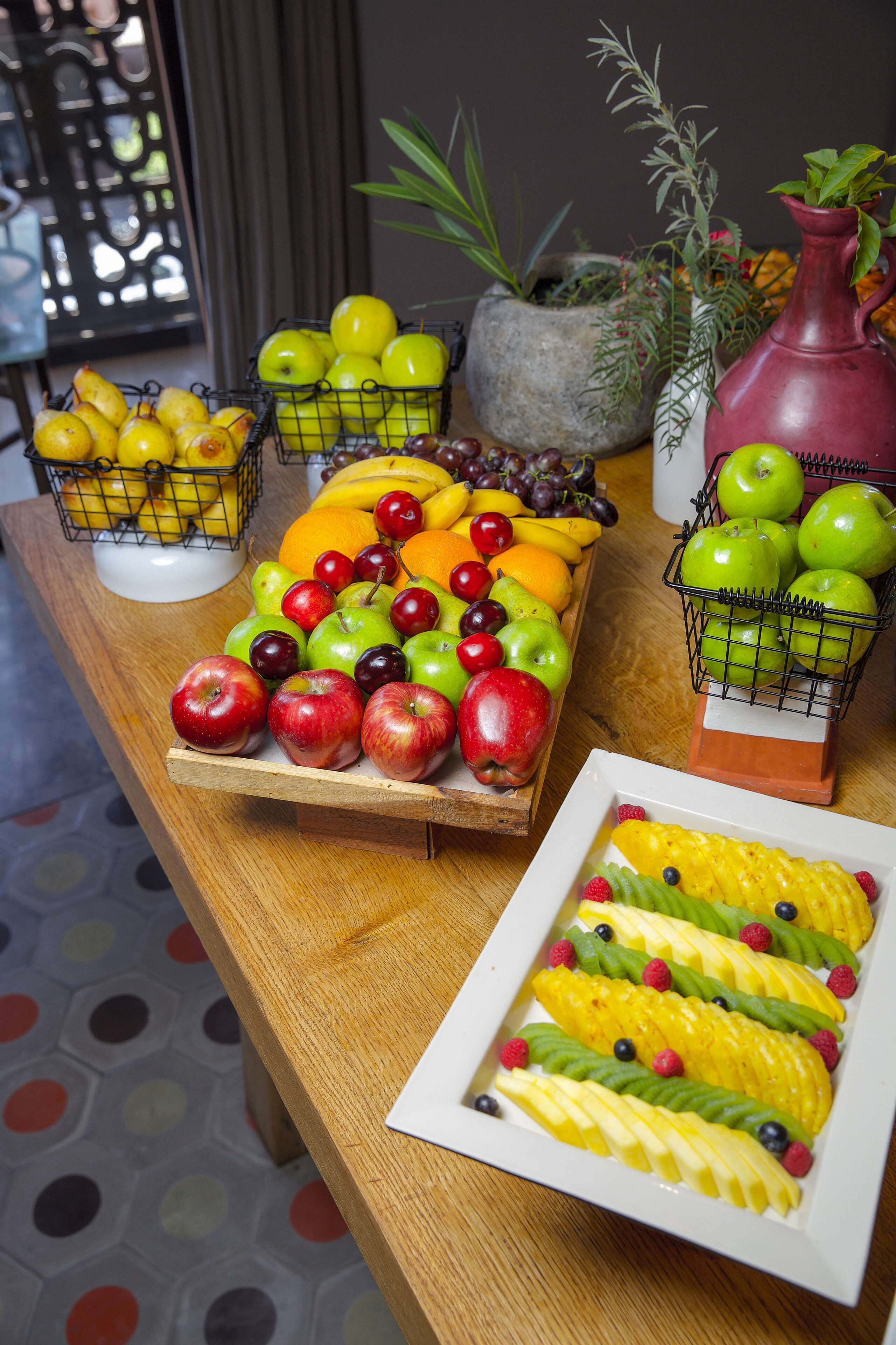 A wooden table with various fruits and vegetables, including apples, oranges, and bananas.