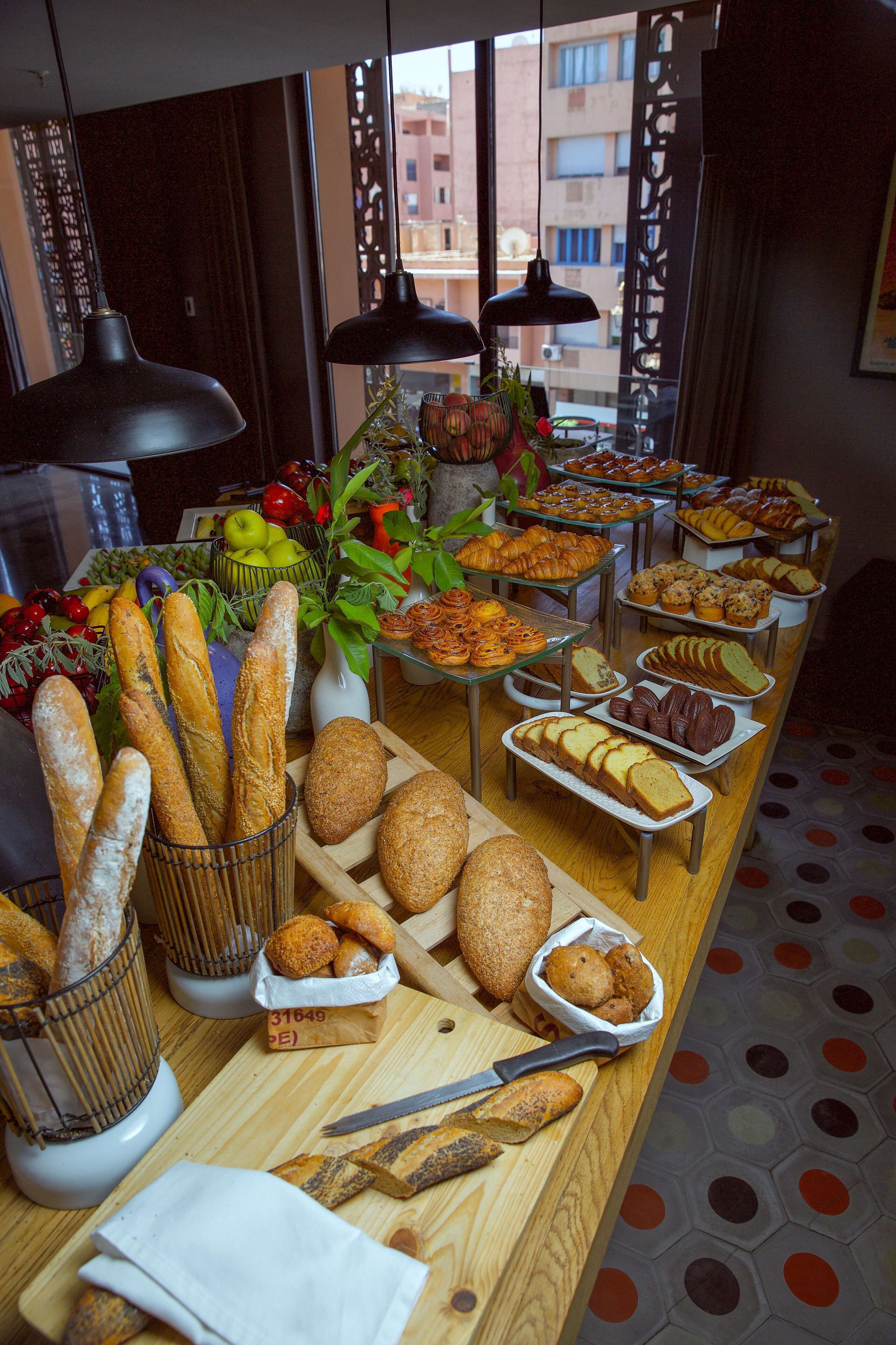 Una mesa de buffet con panes, pasteles y frutas variadas.