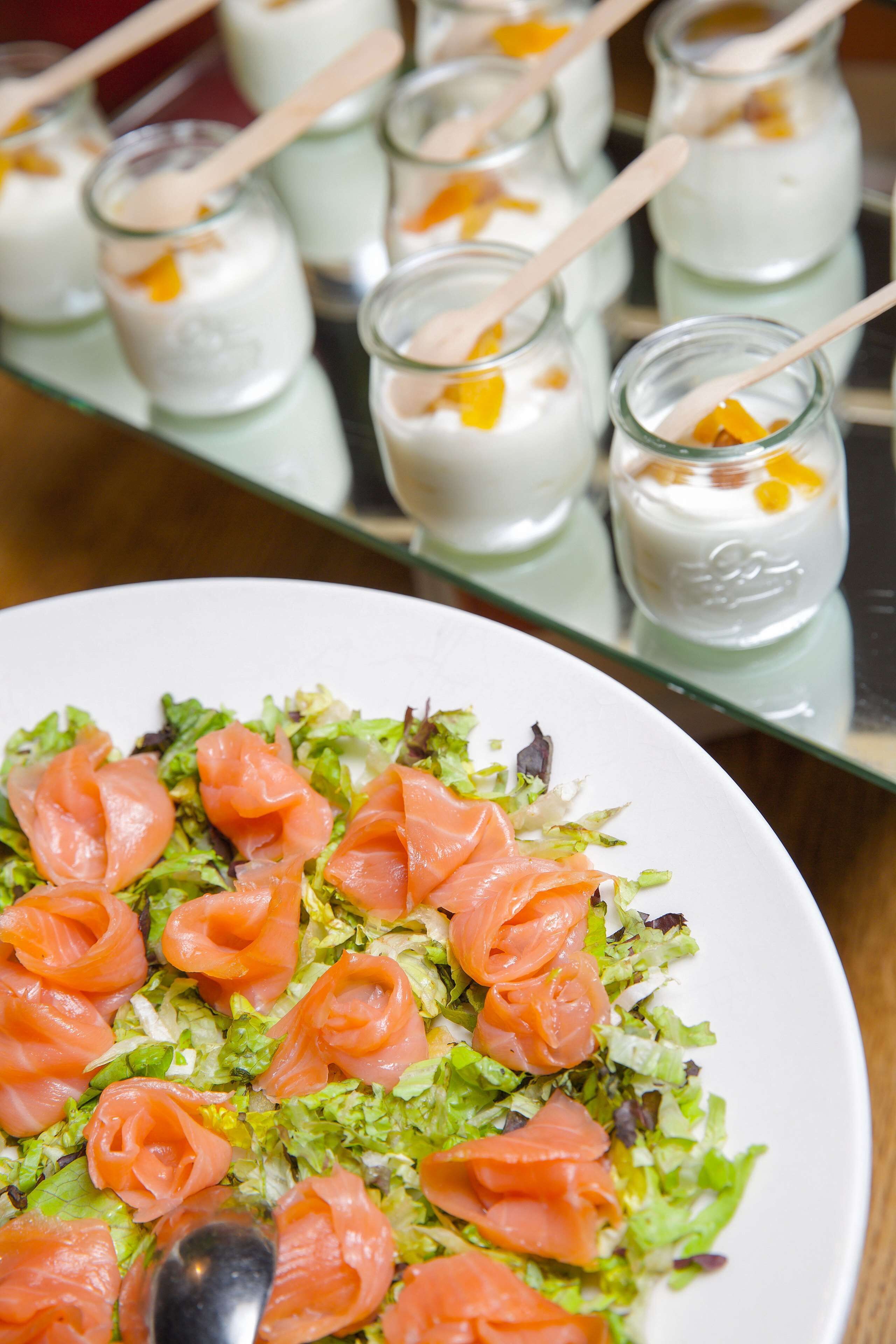 Ein Salat mit Lachs und eine Glasplatte mit Joghurtgläsern.