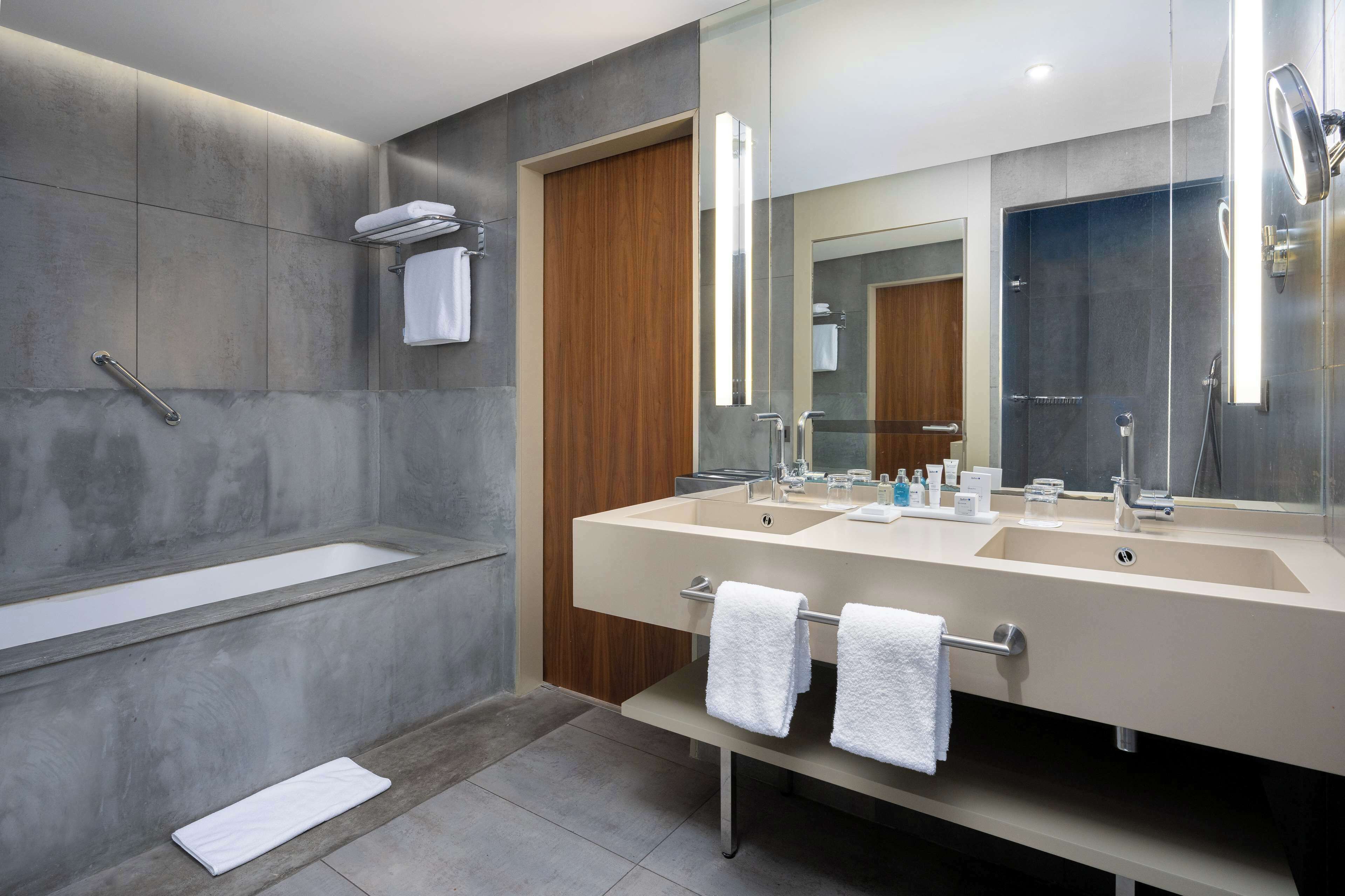Un bagno moderno con una grande vasca, un mobile bagno doppio e un ampio specchio.