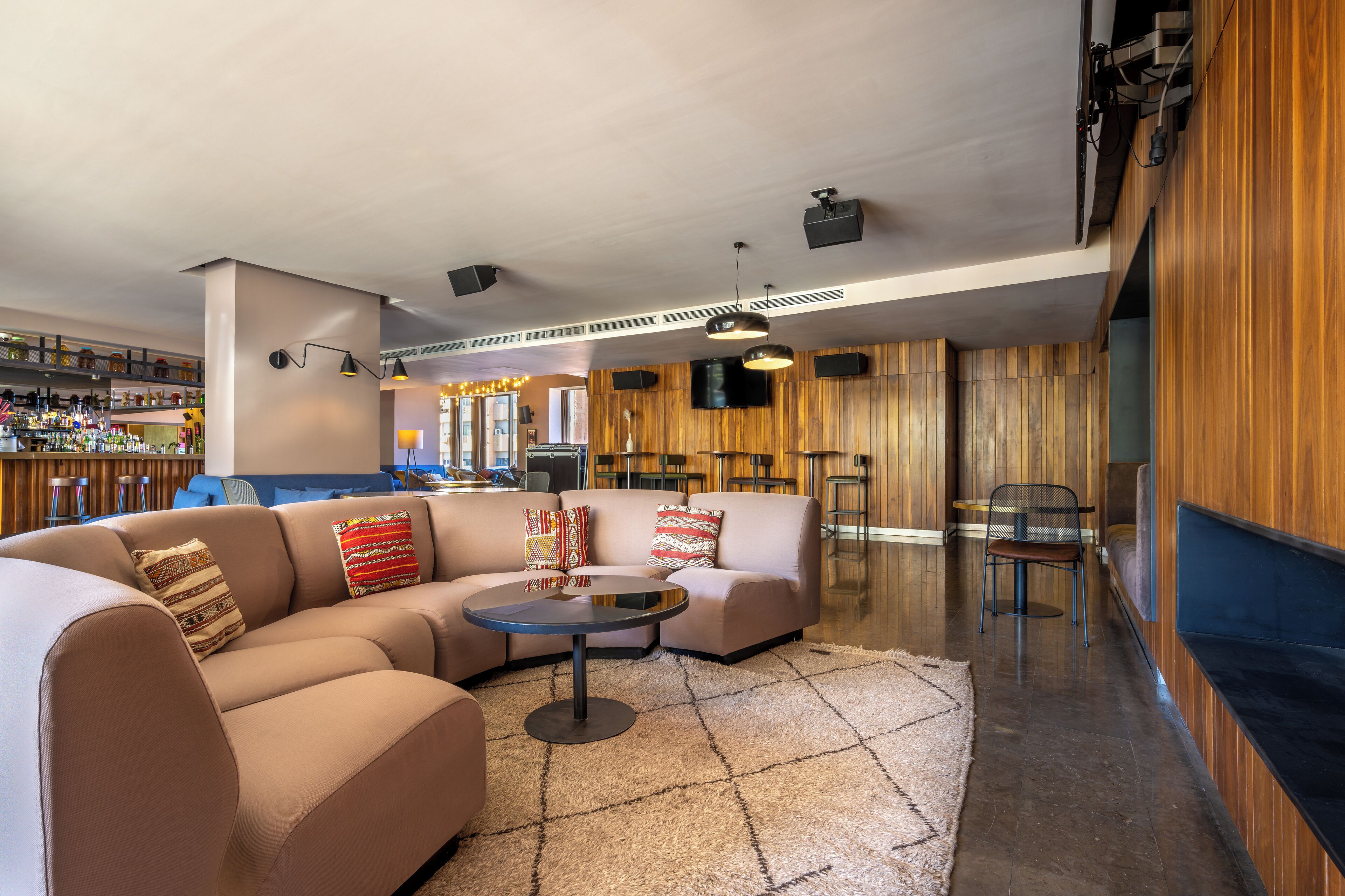 A modern lounge area with a sofa, round table, and bar with stools.