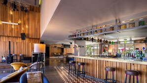 A modern bar area with wooden accents, a checkered floor, and bar stools. - Radisson Blu Hotel, Marrakech Carré Eden (Marrakech)