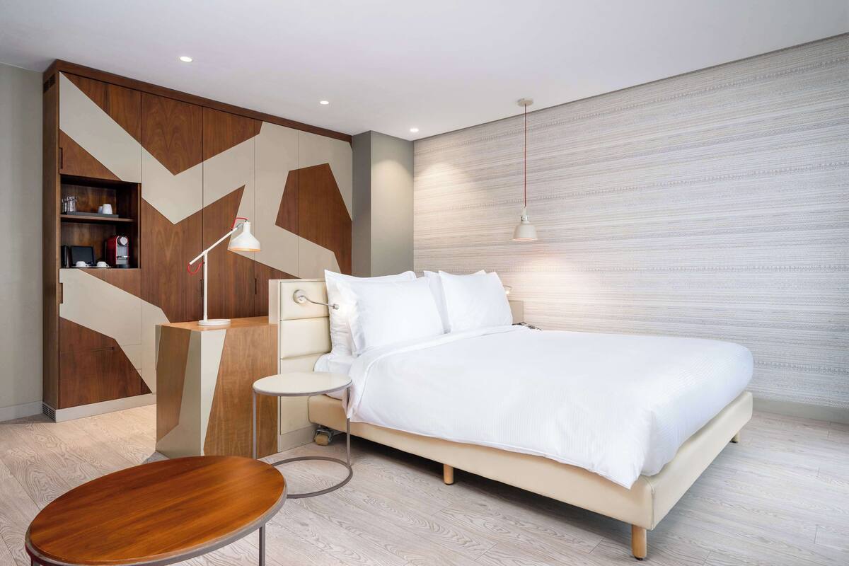 Une chambre moderne avec un lit, une table de chevet, une lampe et des étagères intégrées.
