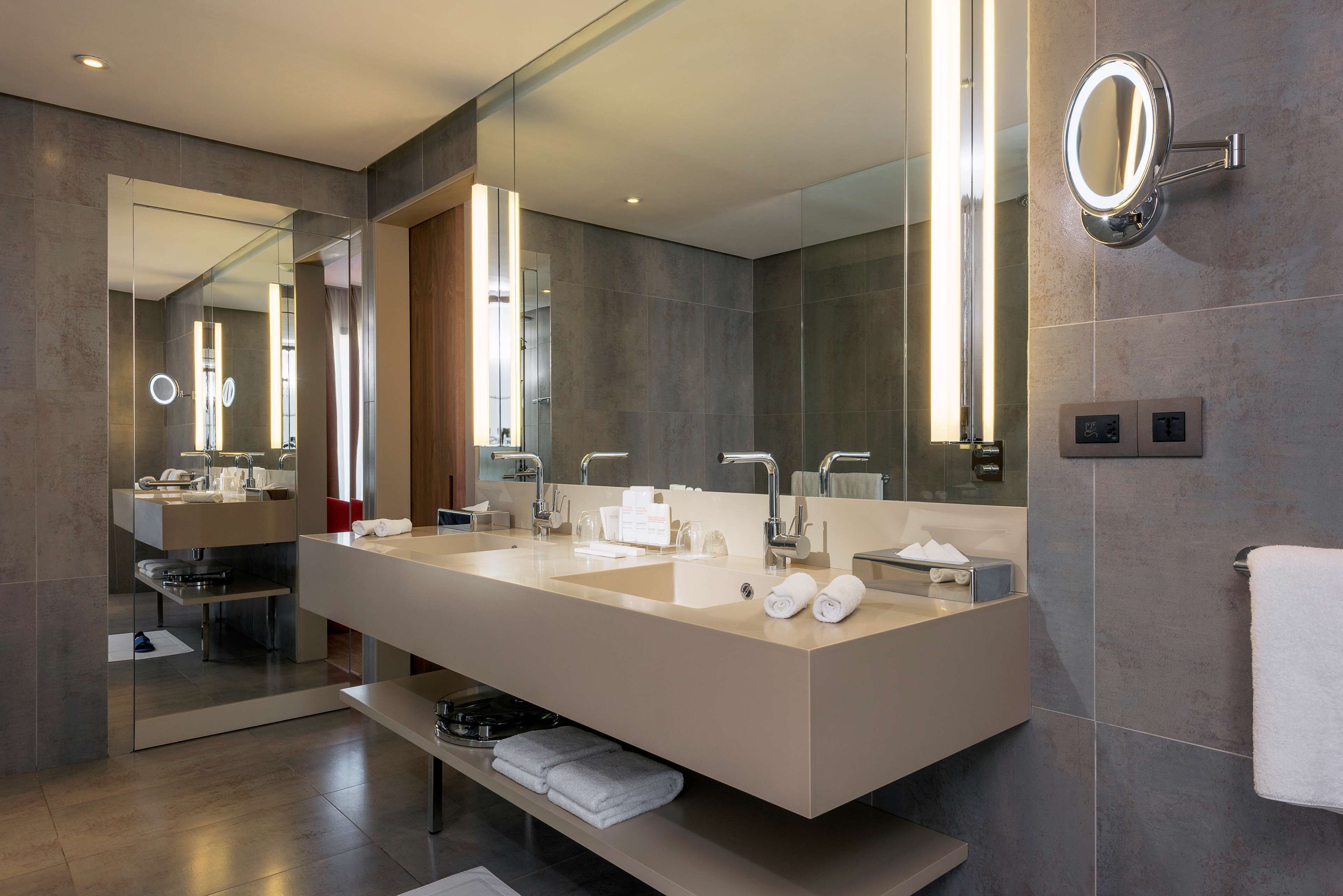 A modern bathroom with a large mirror, two sinks, and a vanity.