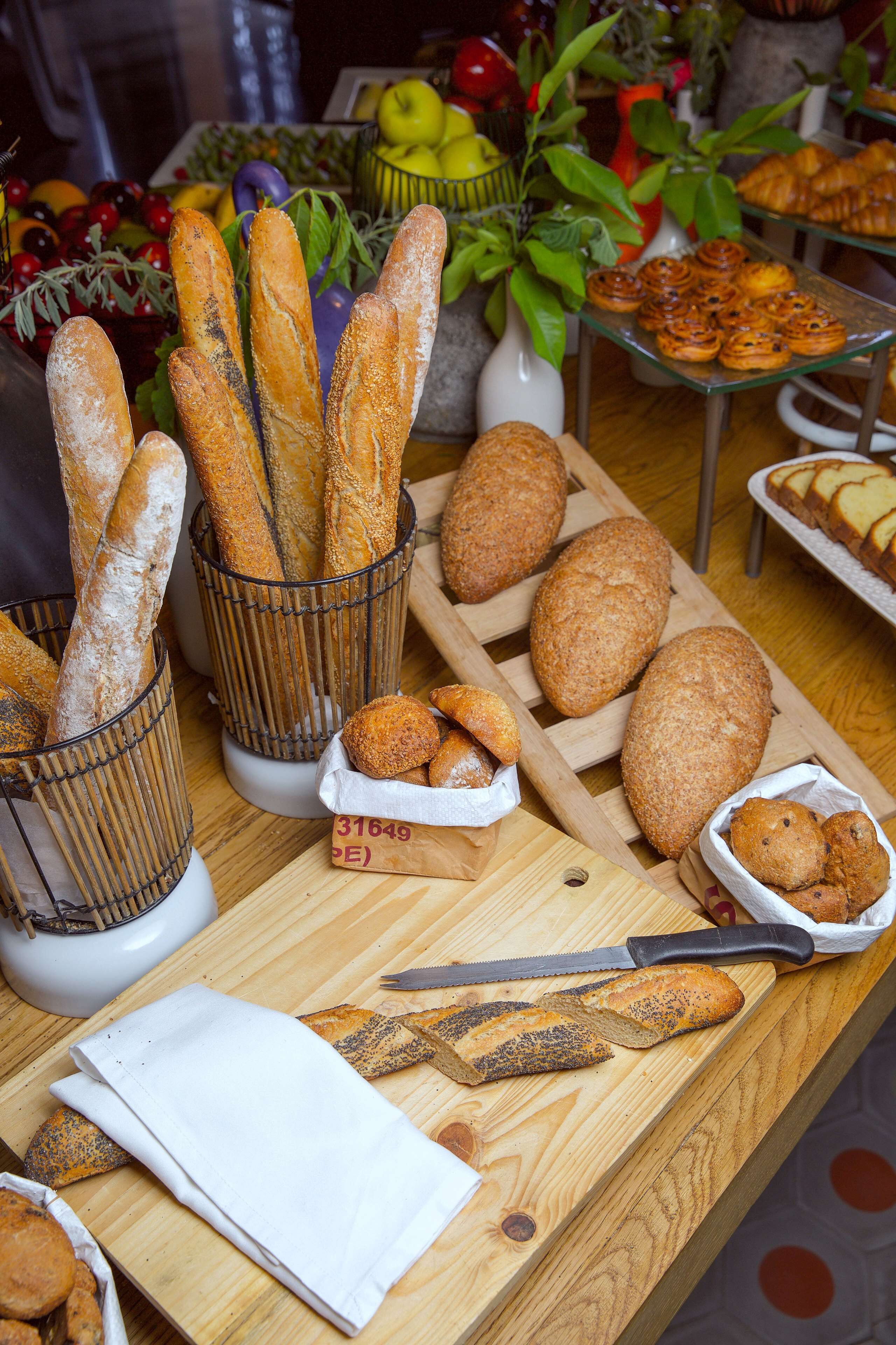Ein Tisch mit verschiedenen Brotsorten und Gebäck, ein Schneidebrett und ein Messer.