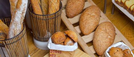 A table with various breads and pastries, a cutting board, and a knife.