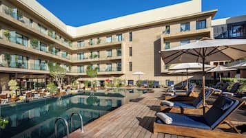 Alberca al aire libre, sombrillas en la alberca y camastros