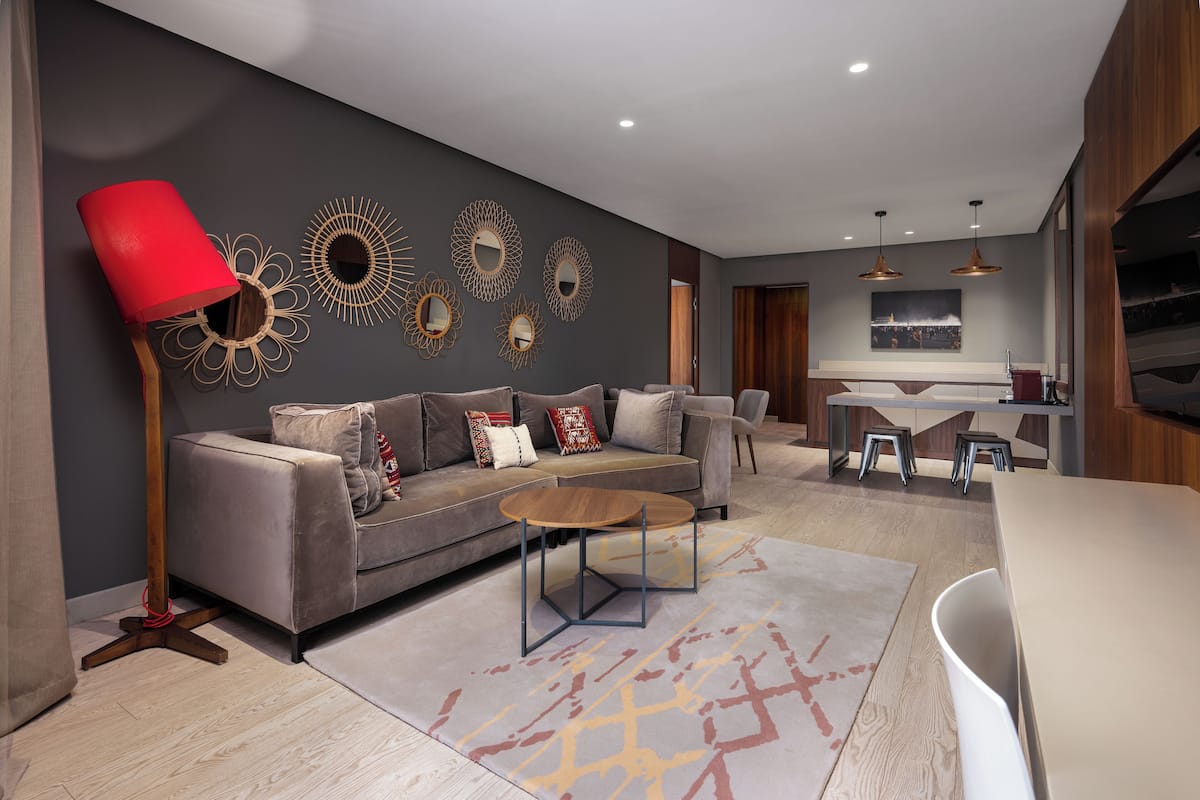 Un salon moderne avec un canapé gris, une table basse en bois et un lampadaire rouge.