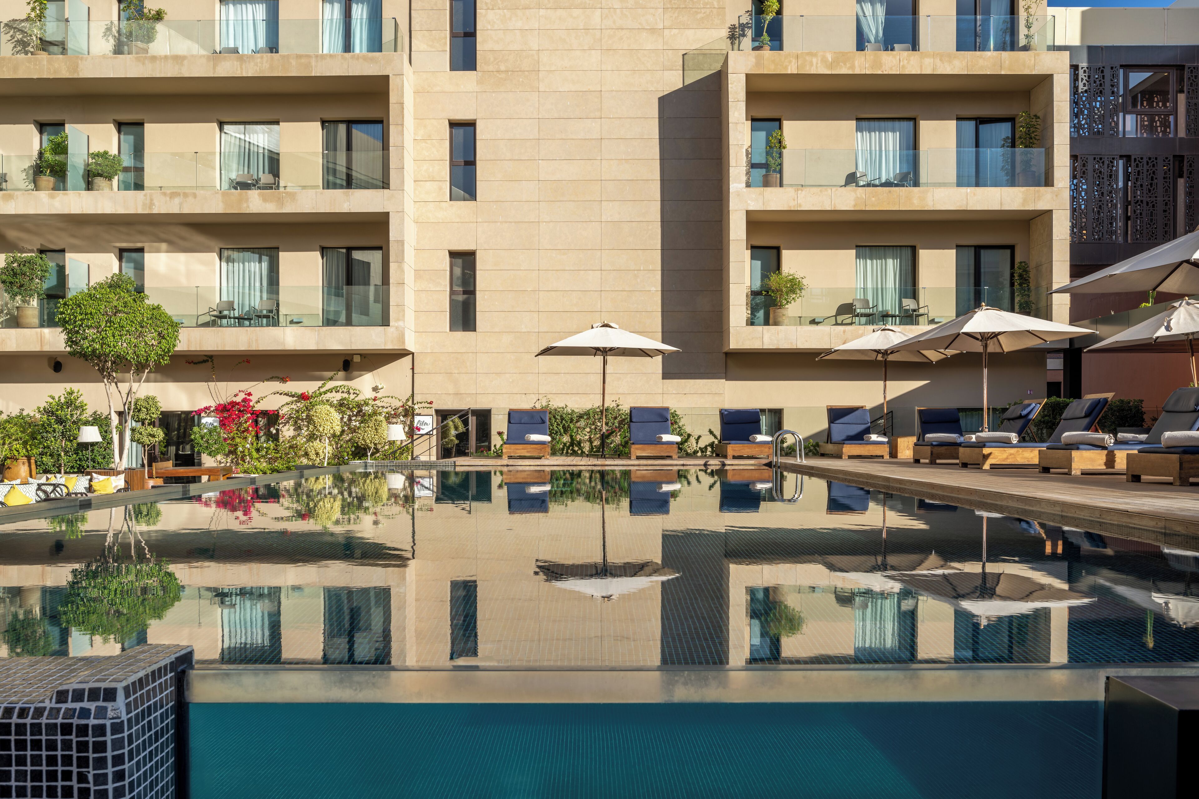 Una piscina al aire libre, sombrillas, sillones reclinables de piscina